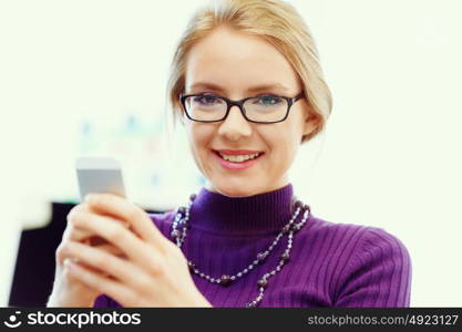 Business woman in office holding mobile phone. Young business woman in office holding mobile phone