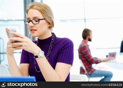 Business woman in office holding mobile phone. Young business woman in office holding mobile phone