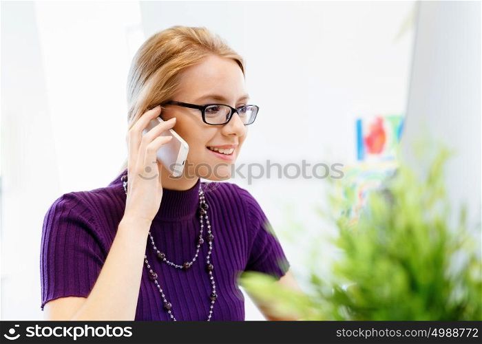 Business woman in office holding mobile phone. Young business woman in office holding mobile phone