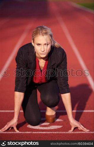 business woman in start position ready to run and sprint on athletics racing track