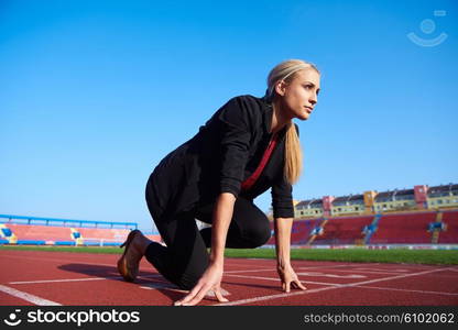 business woman in start position ready to run and sprint on athletics racing track