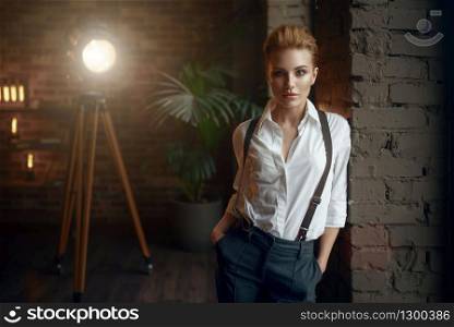 Business woman in strict clothes poses at the window in studio, retro fashion, gangster style. Vintage lady in office with brick walls. Business woman in strict clothes at the window