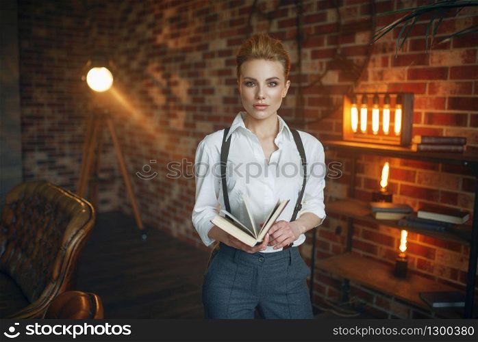 Business woman in strict clothes poses with book in studio, retro fashion, gangster style. Vintage lady in office with brick walls. Business woman in strict clothes poses with book