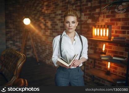 Business woman in strict clothes poses with book in studio, retro fashion, gangster style. Vintage lady in office with brick walls. Business woman in strict clothes poses with book