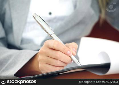 Business woman in suit writing notes with pen on document paper. Business woman writing notes