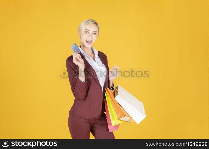 Business woman is happy with shopping in studio yellow background