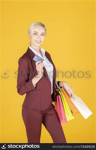 Business woman is happy with shopping in studio yellow background