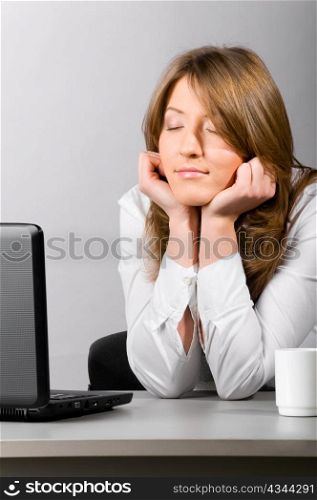business woman is sitting in the office with laptop and sleeping with head on hands