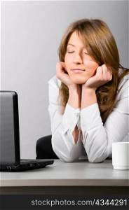 business woman is sitting in the office with laptop and sleeping with head on hands
