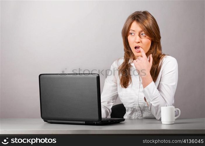 business woman is sitting in the office with laptop and thoughtfully looking at screen