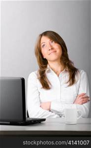 business woman is sitting in the office with laptop and thoughtfully looking sideways