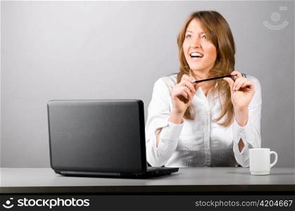 business woman is sitting in the office with laptop and thoughtfully looking sideways