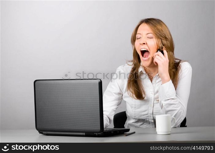 business woman is sitting in the office with laptop and yawning