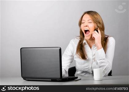 business woman is sitting in the office with laptop and yawning