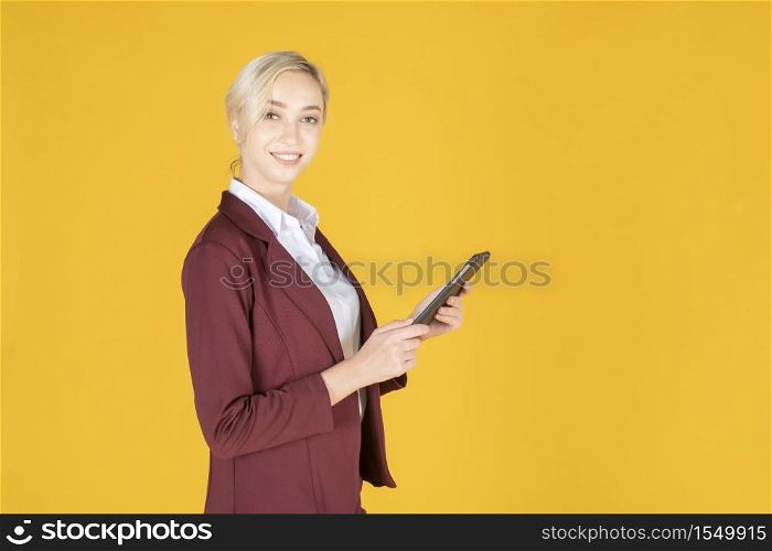 Business woman is using tablet in studio yellow background
