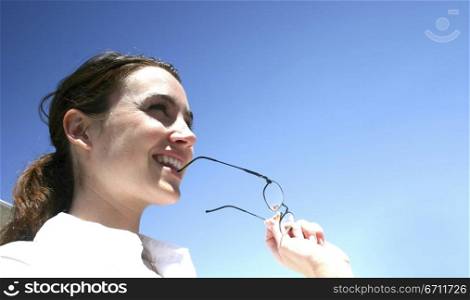 Business woman is wearing a white shirt and is biting her glasses.
