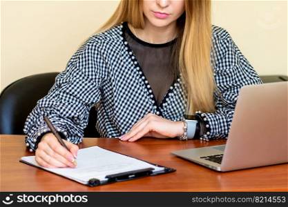 Business woman is writing on a document with laptop at home office.. Business woman is writing on a document