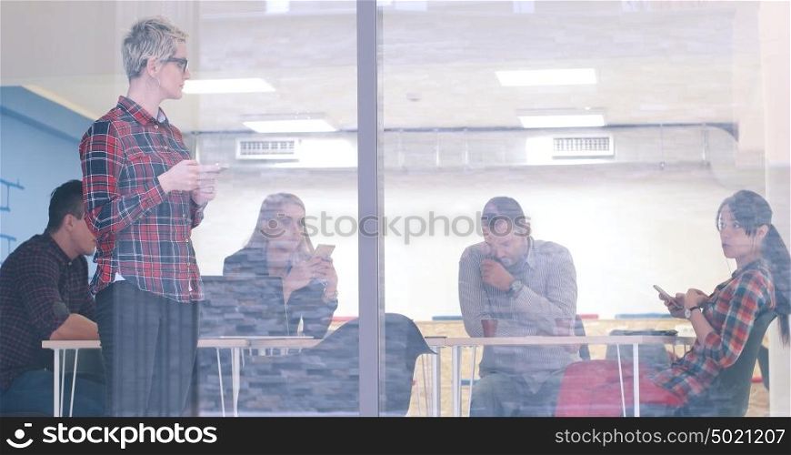 Business Woman Looking Through A Window And using On A Cell Phone during bussines meeting