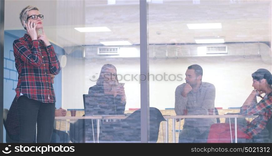 Business Woman Looking Through A Window And using On A Cell Phone during bussines meeting