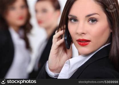 Business woman making call colleagues in background