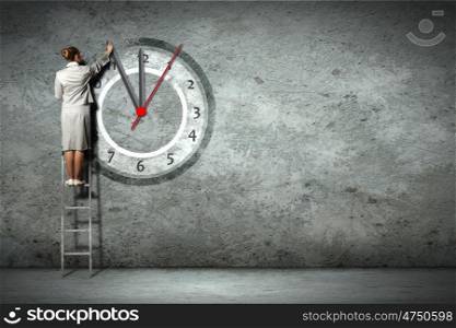 Business woman on ladder. Businesswoman standing on ladder moving hands of clock