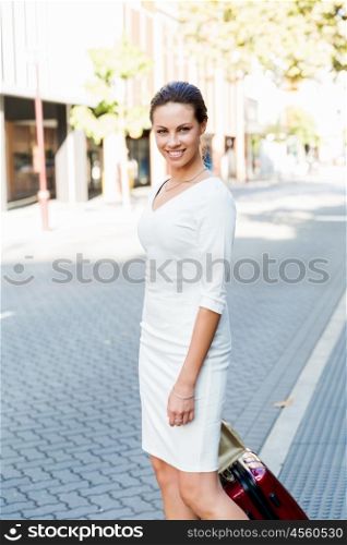 Business woman pulling suitcase bag walking in city. Young business woman pulling suitcase walking in urban city