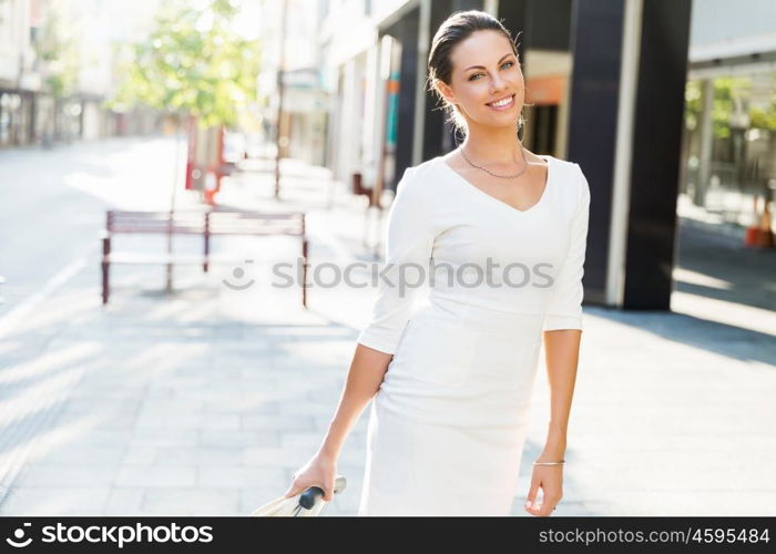 Business woman pulling suitcase bag walking in city. Young business woman pulling suitcase walking in urban city