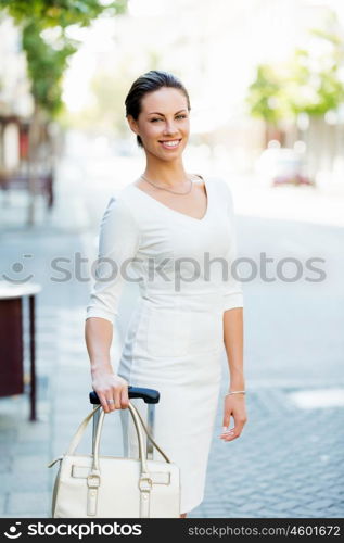 Business woman pulling suitcase bag walking in city. Young business woman pulling suitcase walking in urban city