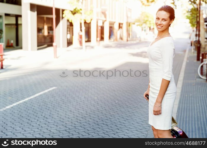 Business woman pulling suitcase bag walking in city. Young business woman pulling suitcase walking in urban city