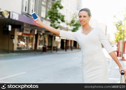 Business woman pulling suitcase bag walking in city. Young business woman with suitcase in city looking for taxi