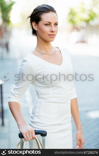 Business woman pulling suitcase bag walking in city. Young business woman pulling suitcase walking in urban city