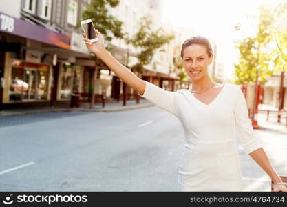 Business woman pulling suitcase bag walking in city. Young business woman with suitcase in city looking for taxi