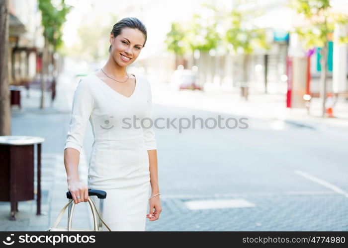 Business woman pulling suitcase bag walking in city. Young business woman pulling suitcase walking in urban city