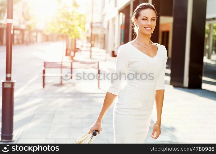 Business woman pulling suitcase bag walking in city. Young business woman pulling suitcase walking in urban city