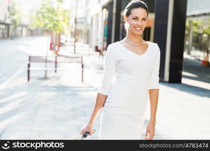 Business woman pulling suitcase bag walking in city. Young business woman pulling suitcase walking in urban city