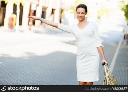Business woman pulling suitcase bag walking in city. Young business woman with suitcase in city looking for taxi