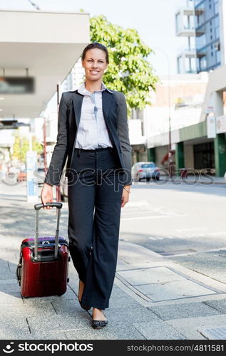 Business woman pulling suitcase bag walking in city. Young business woman pulling suitcase walking in urban city