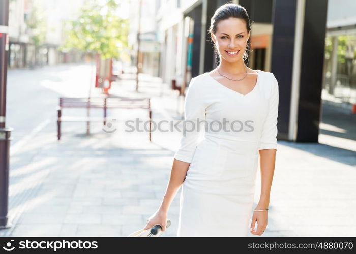 Business woman pulling suitcase bag walking in city. Young business woman pulling suitcase walking in urban city