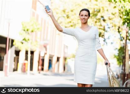 Business woman pulling suitcase bag walking in city. Young business woman with suitcase in city looking for taxi