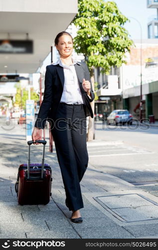 Business woman pulling suitcase bag walking in city. Young business woman pulling suitcase walking in urban city