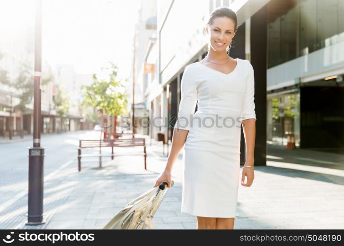 Business woman pulling suitcase bag walking in city. Young business woman pulling suitcase walking in urban city