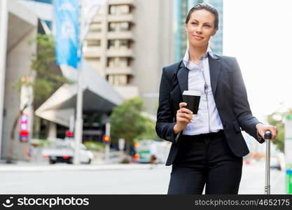 Business woman pulling suitcase walking in city. Young business woman pulling suitcase walking in urban city