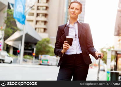 Business woman pulling suitcase walking in city. Young business woman pulling suitcase walking in urban city
