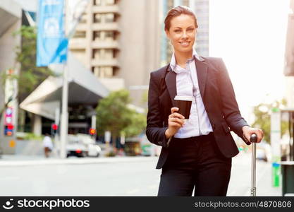 Business woman pulling suitcase walking in city. Young business woman pulling suitcase walking in urban city