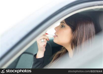 Business woman retouching her makeup while stopped in the traffic