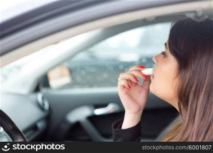 Business woman retouching her makeup while stopped in the traffic