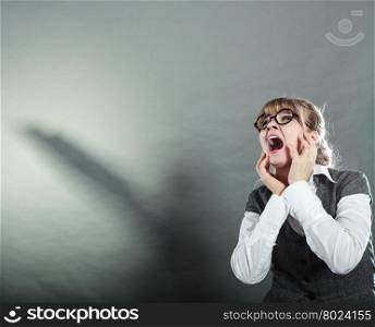 Business woman screaming looking upward in full fear wide open mouth grey wall background.