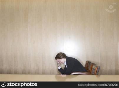 Business woman sitting in the chair with her hands in on her head in distress