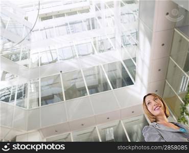 Business woman standing in atrium of office building low angle view
