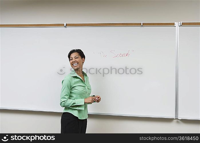 Business woman standing in front of whiteboard, laughing